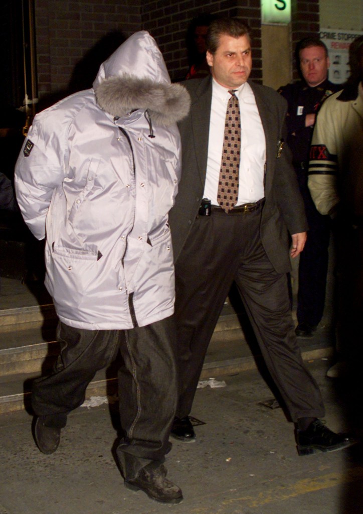 The walk never changed: led from Manhattan South after his December 1999 arrest — hood up, fur on the puffer. Photo: Reuters, editorial use.